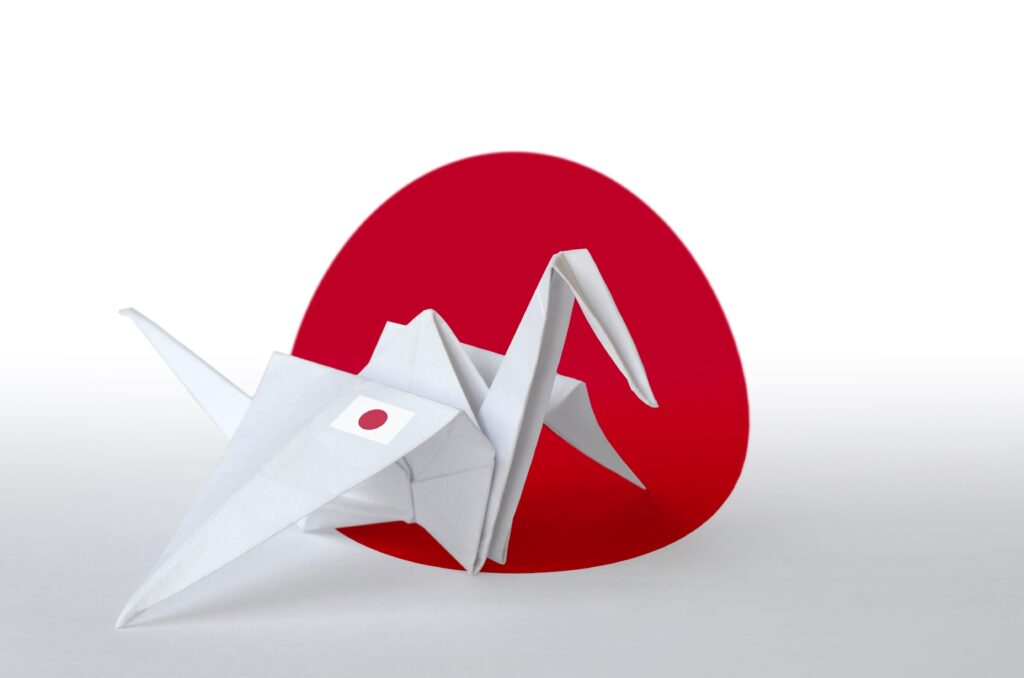 japan flag depicted on paper origami crane wing o 2022 11 14 16 02 38 utc Japan flag depicted on paper origami crane wing. Oriental handmade arts concept
