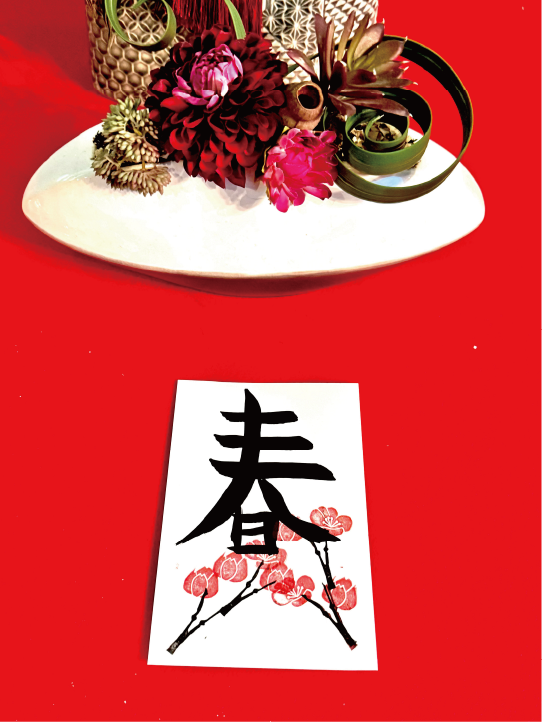 Calligraphy postcard featuring the kanji ‘haru’ (春), decorated with cherry-blossom stamps in a black frame at Shodocafe7557 in Roppongi, Tokyo.