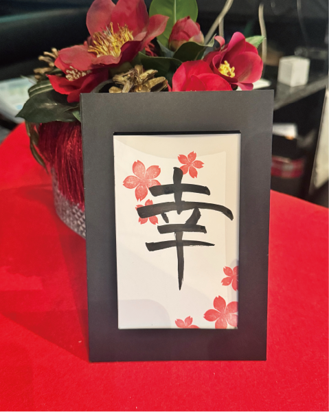 Calligraphy postcard featuring the kanji ‘siawase’ (幸), decorated with cherry-blossom stamps in a black frame at Shodocafe7557 in Roppongi, Tokyo.