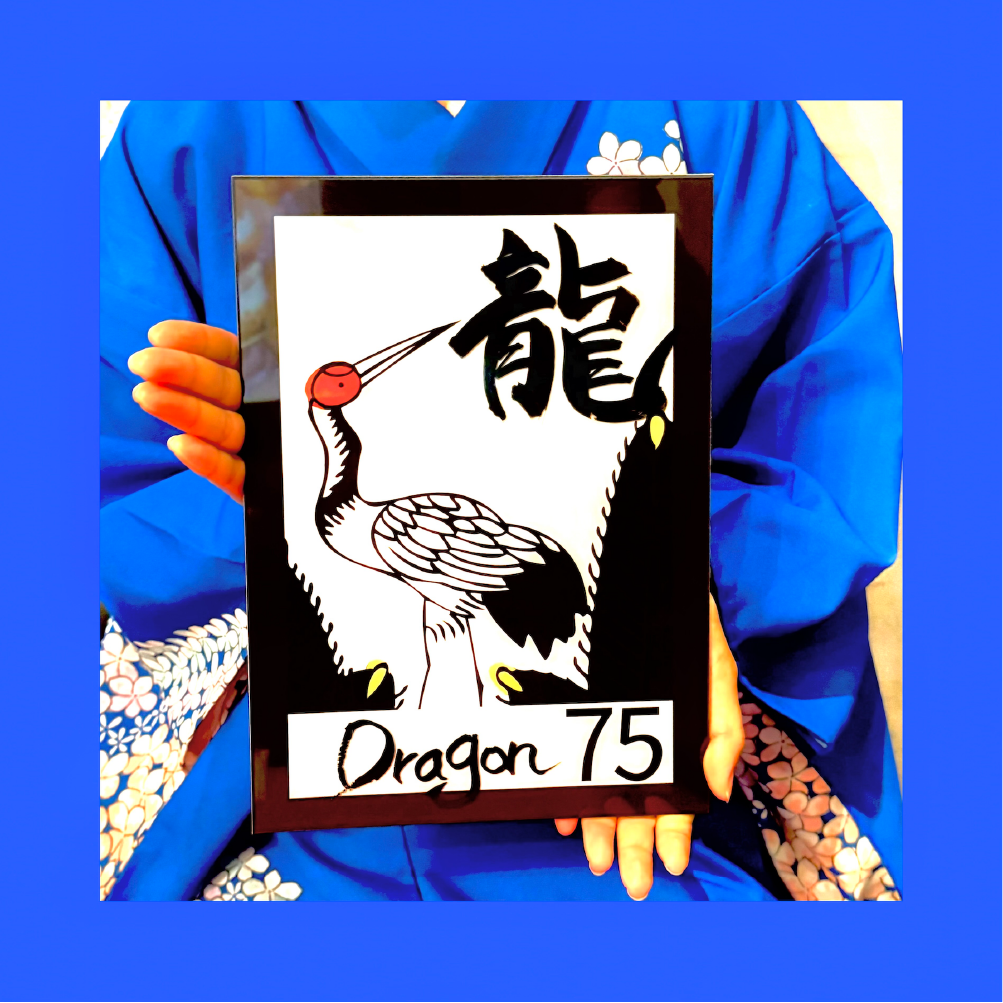 shodocafe7557 hanafuda calligraphy plate Guest in a blue kimono holds a framed original calligraphy plate featuring a Hanafuda-inspired crane design and the kanji ‘龍’ at Shodocafe7557 in Roppongi, Tokyo.