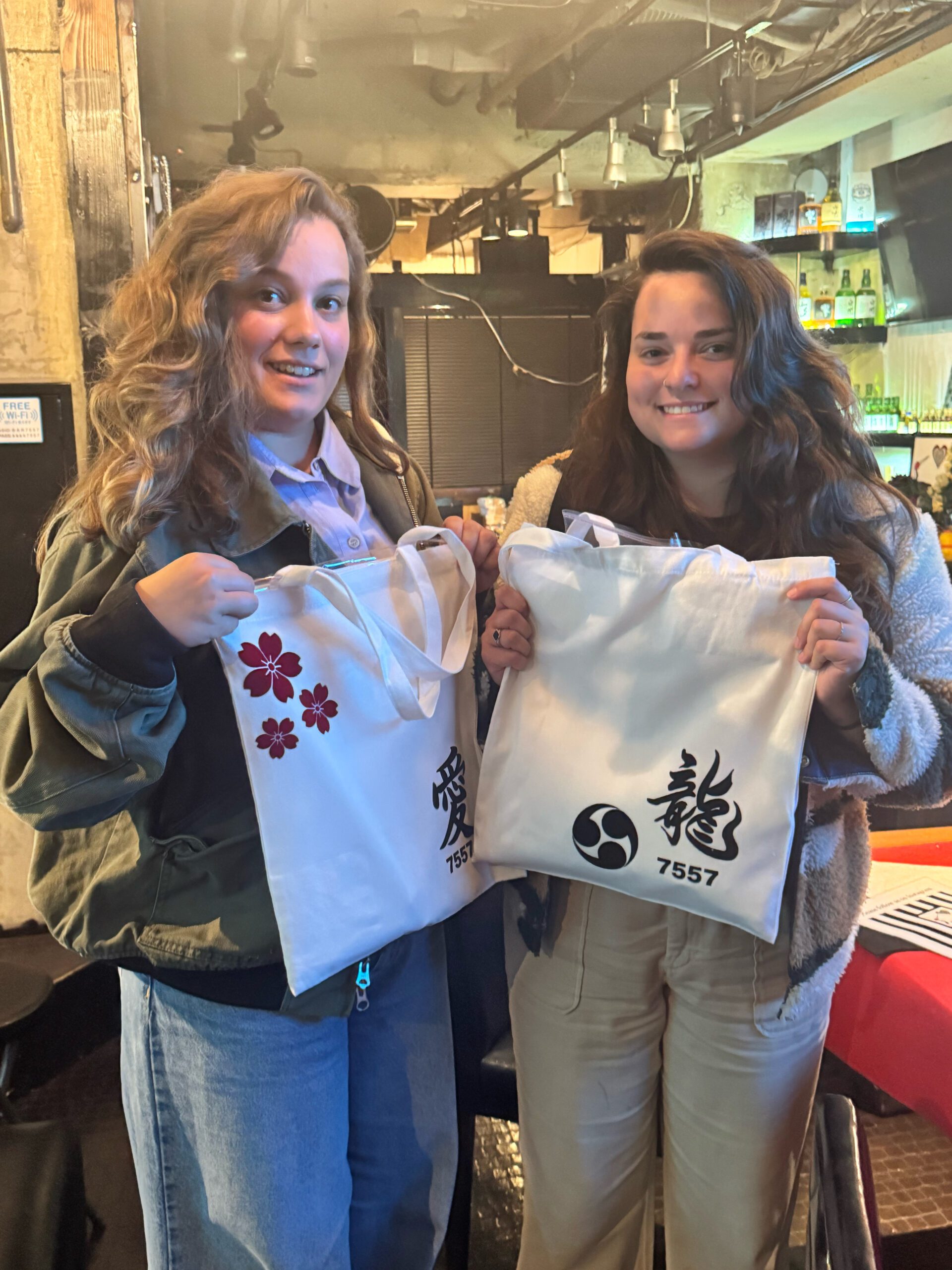 two female friends smiling with kanji tote bags scaled Friends Showing “Love” & “Dragon” Kanji Totes – Shodocafe 7557