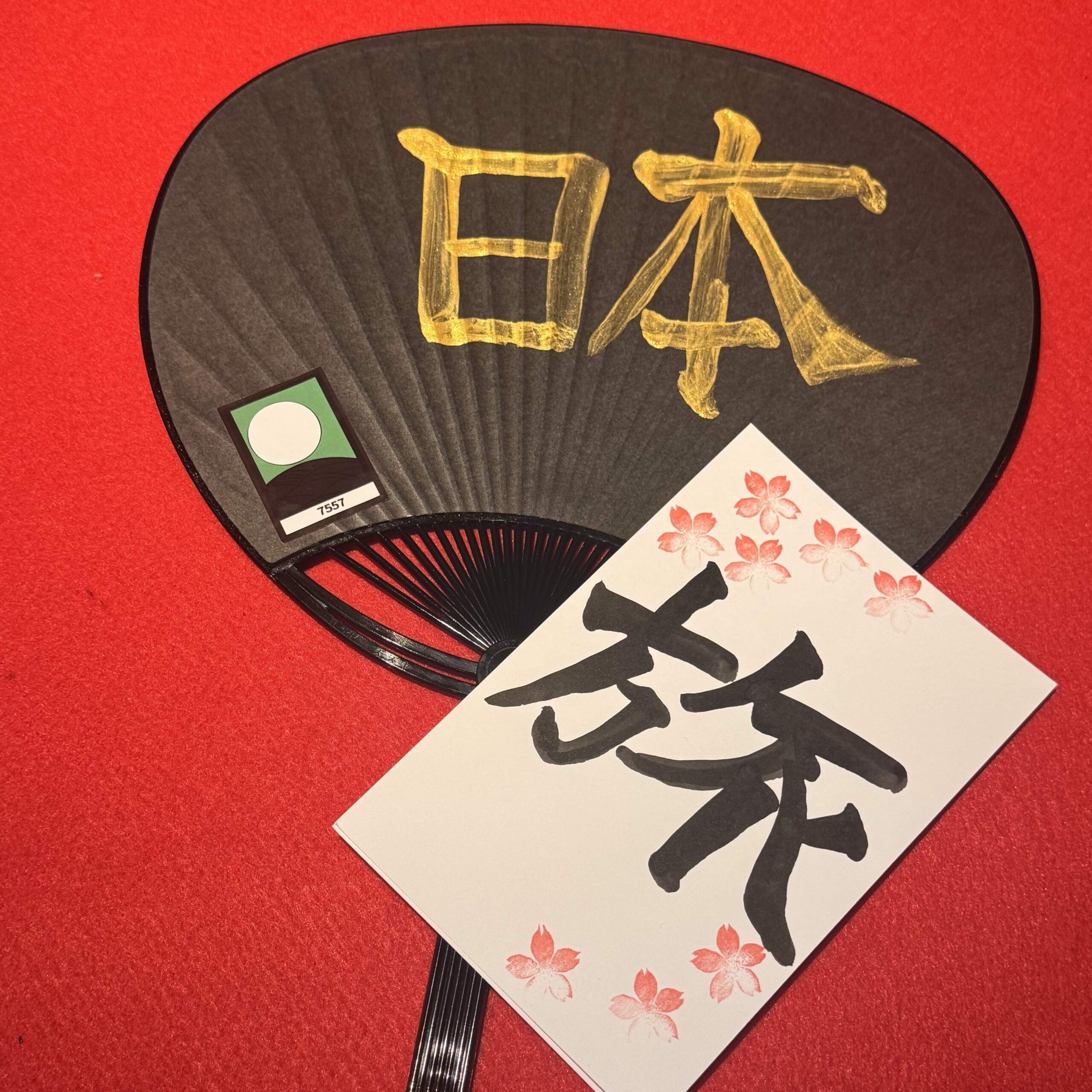 IMG 4411 1 scaled Gold ‘Japan’ (日本) kanji painted on a black uchiwa fan with a cherry-blossom ‘旅’ card, created in the hotel-guest calligraphy workshop at Shodocafe7557, Tokyo.
