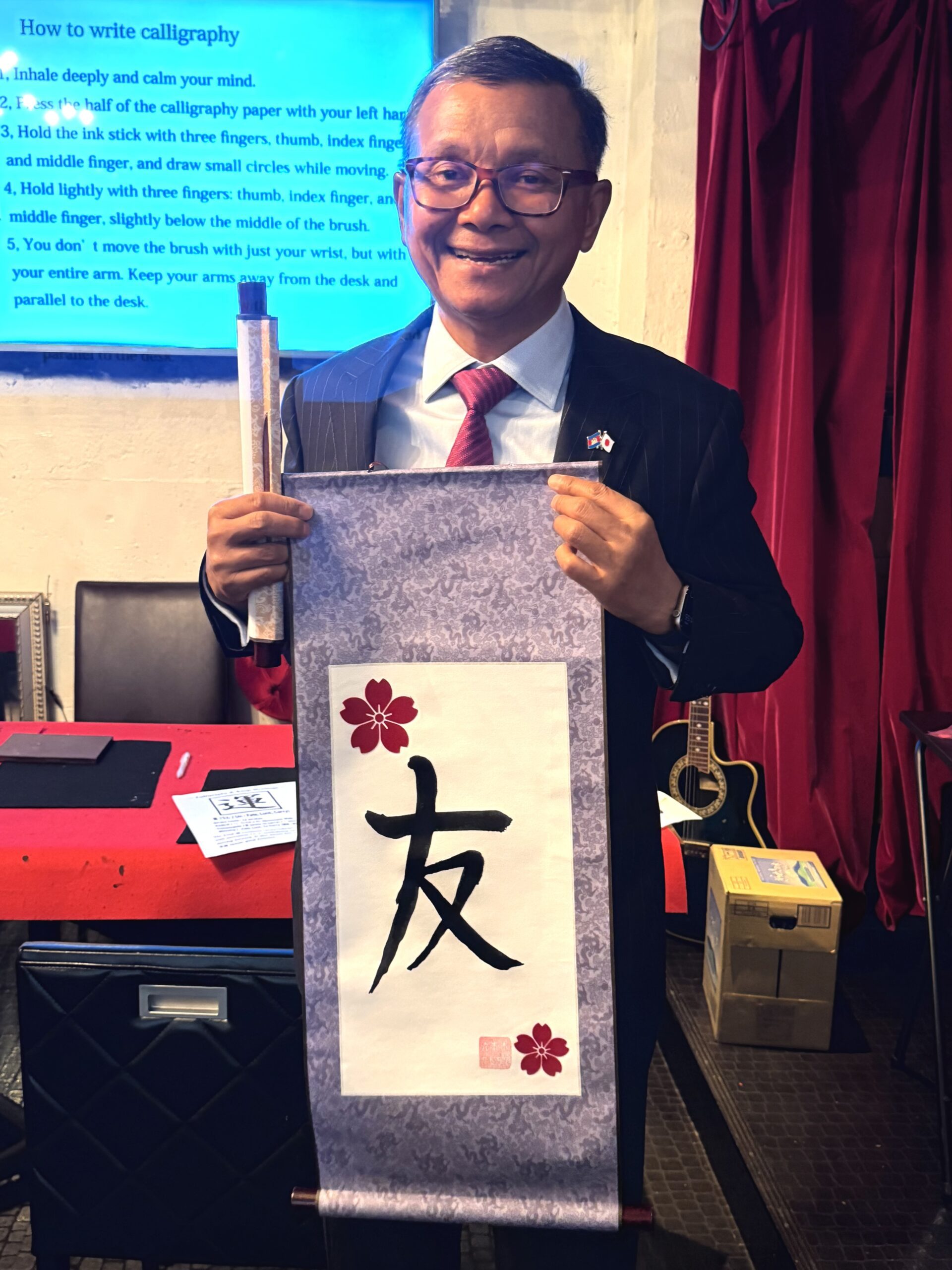 Dr. Hang Chuon Naron, Cambodian Deputy Prime Minister, holding his Japanese calligraphy scroll featuring the Kanji "Friend" (友) at Shodocafe7557 in Roppongi, Tokyo.