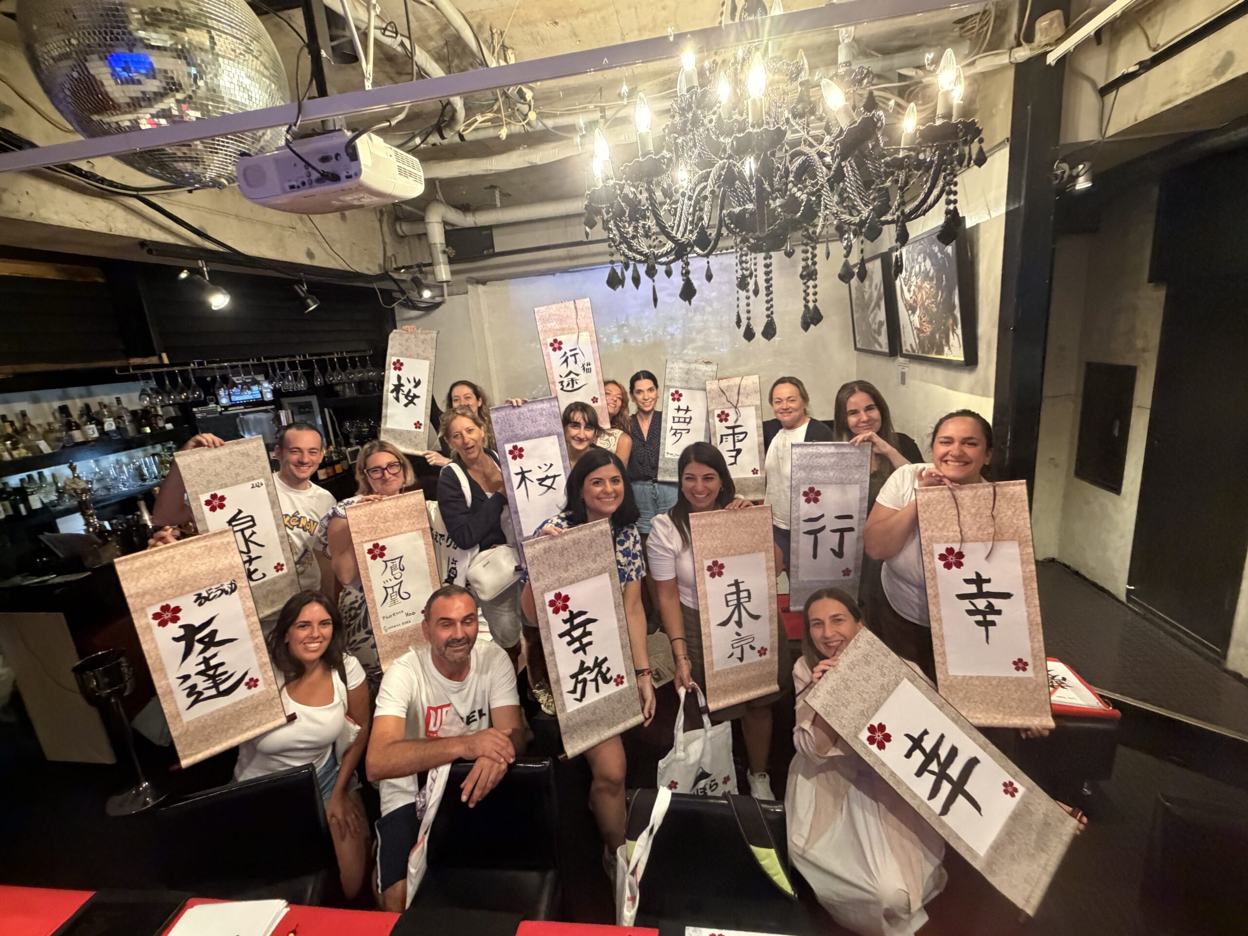 group calligraphy experience 16 guests shodocafe7557 tokyo scaled 16 guests enjoying a private group Japanese calligraphy experience at Shodocafe7557 in Roppongi, Tokyo, holding their handmade Kanji hanging scrolls.